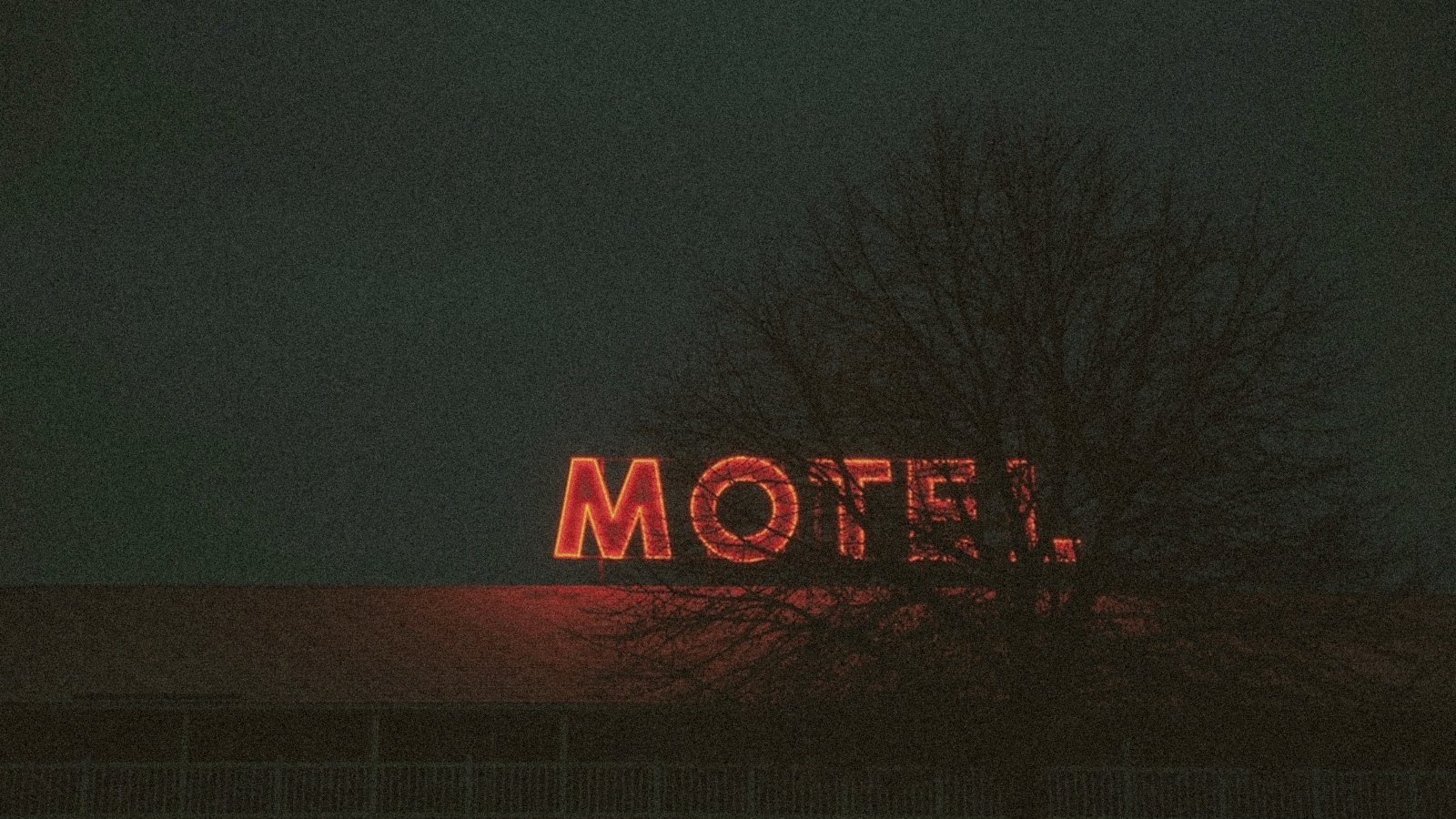 A motel sign glowing red in fog