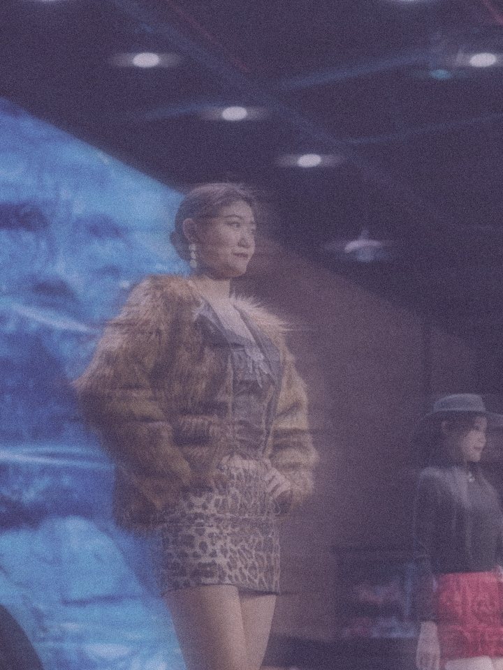 Model in a fur coat on stage, in lilac haze